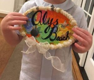 A kid holding a décor with Alys Beach